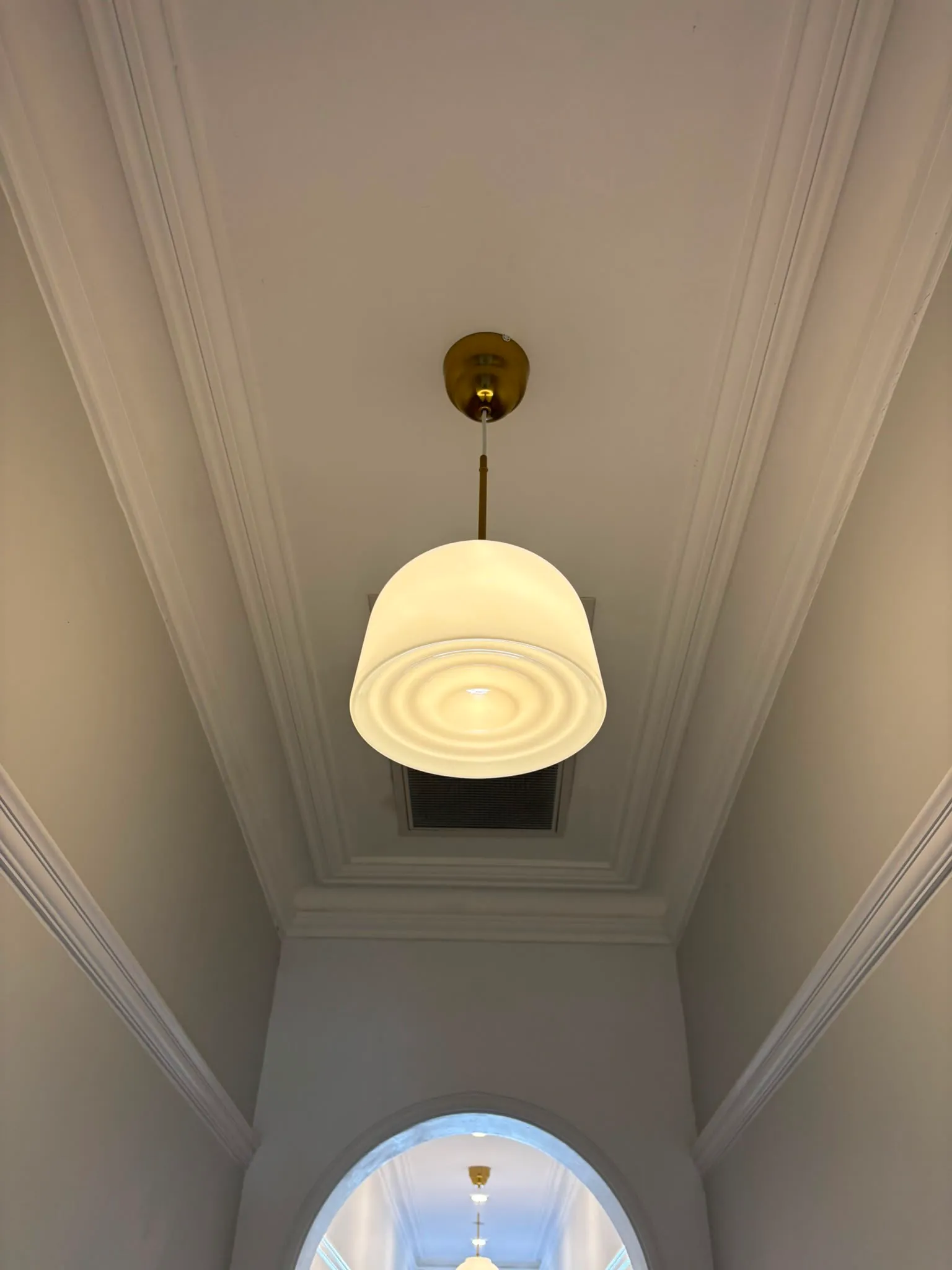 Brass pendant light in a Federation hallway with ornate ceiling cornicing