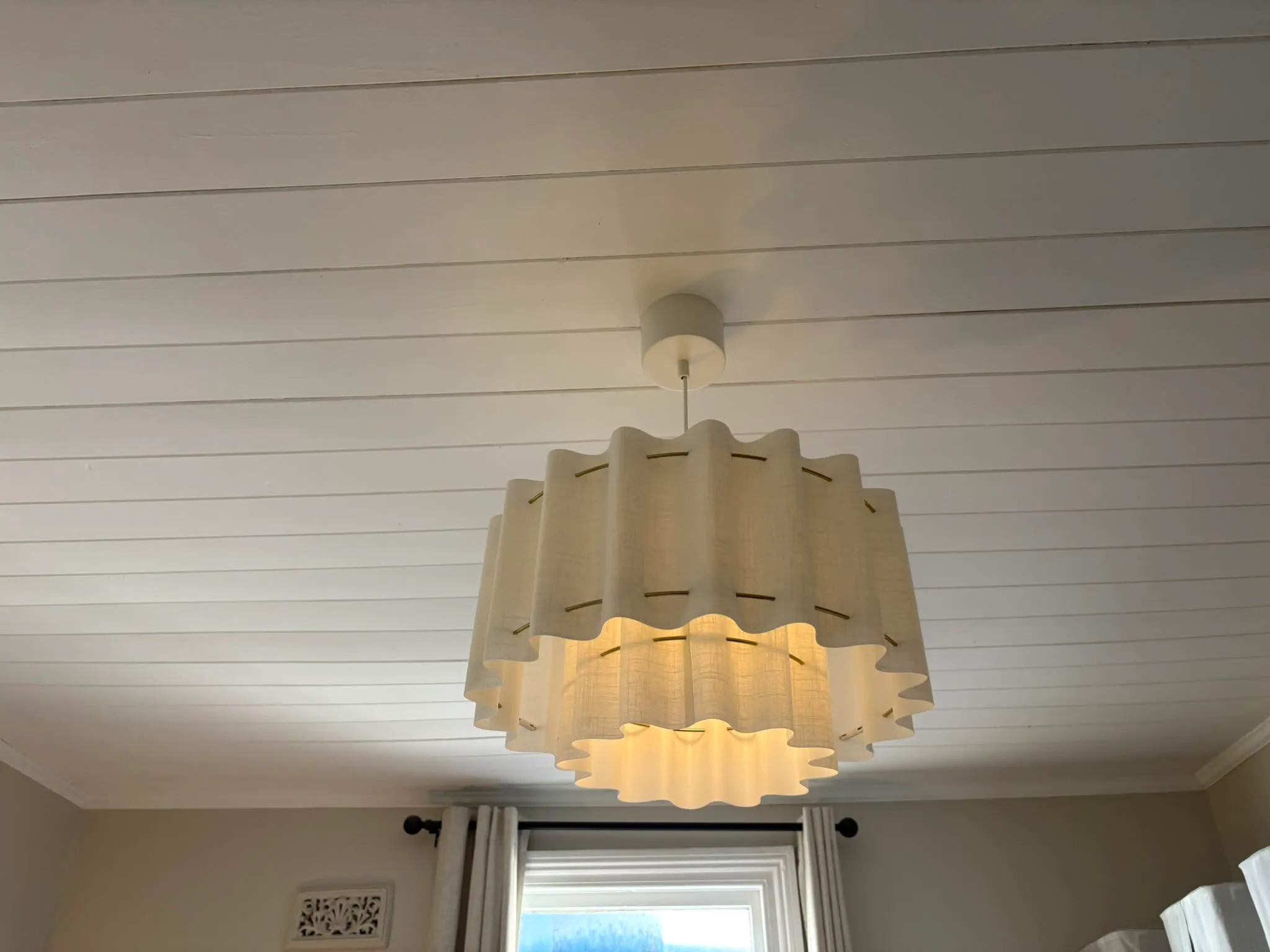 Tiered linen drum pendant light beneath a white VJ board ceiling
